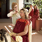 Hairdresser dressing the hair of a woman wearing Roman robes.
