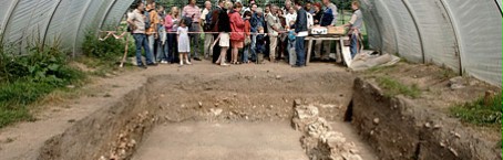 Een groep bezoekers bekijkt tijdens een rondleiding een overdekte opgraving.