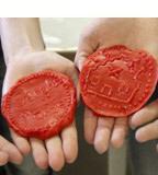 Zwei rote Wachsmünzen mit Verzierungen.