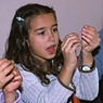 Een meisje buigt een doekspeld van zilverdraad.