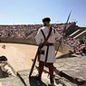 A man dressed as a roman gladiator stands at the entrance of the amphitheater.