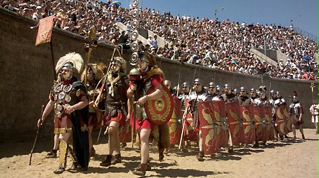 A group of roman soldiers marching into the arena of the amphitheater.