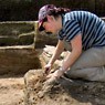Eine Grabungsarbeiterin in römischer Fundschicht.