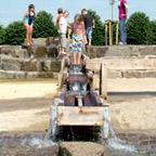 Kinder spielen auf dem Wasserspielplatz.