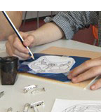 Kinderhände umfahren mit einem Druckstift das Muster auf einem Bogen blauer Folie.