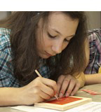 Ein Mädchen ritzt Schriftzeichen in den Wachs einer Schreibtafel.