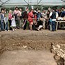 Een groep bezoekers bekijkt een opgraving.
