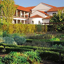 Der grüne Kräutergarten mit der römischen Herberge im Hintergrund.