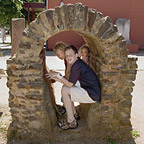 Drie kinderen zitten op de ruines van een echte Romeinse waterleiding.