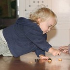 Toddler crawling over a table with Roman board games.