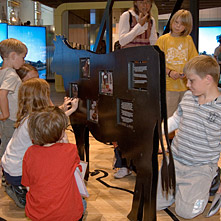 Een groepje kinderen bij een installatie in de vorm van een koe. De installatie is met kleine geïlustreerde panelen bedekt. 