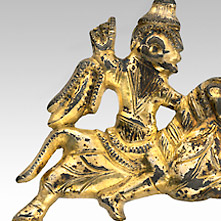 Eine vergoldete Fibel aus Silber in Form eines galoppierenden Reiters.