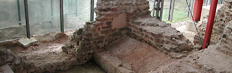 Unearthed foundation walls in front of the glass facade of the protective building