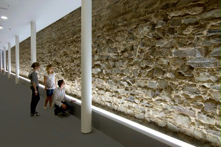 Drie kinderen bekijken de Romeinse fundamenten in het museum.