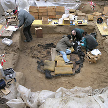 Grabungstechniker arbeiten in einem freigelegten Scheiterhaufengrab aus römischer Zeit.