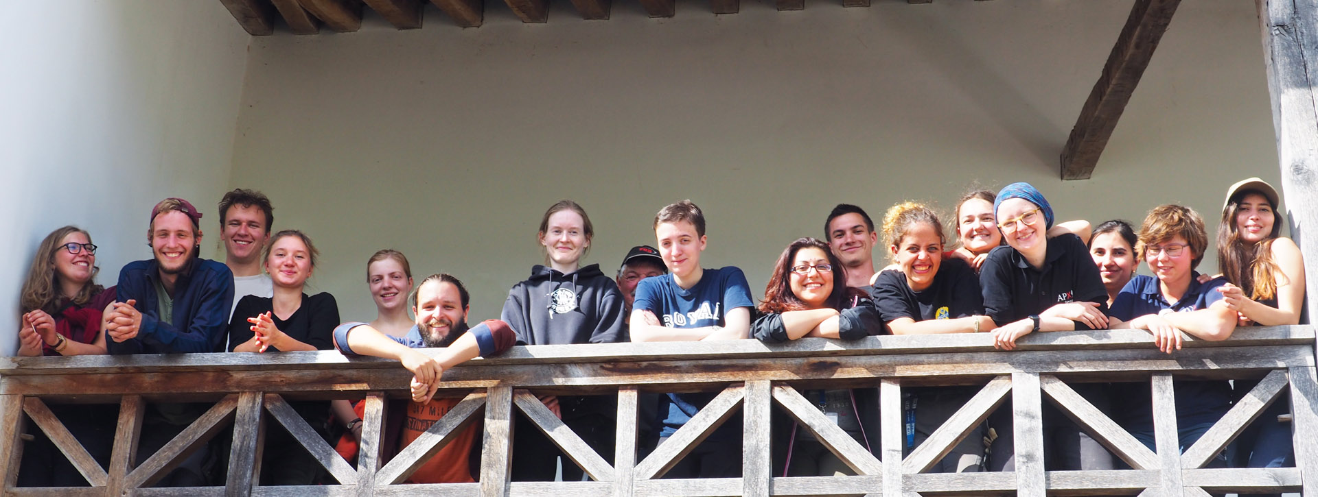 Eine große Gruppe Studierende stehen gut gelaunt auf dem Balkon eines der Handwerkerhäuser und lachen in die Kamera