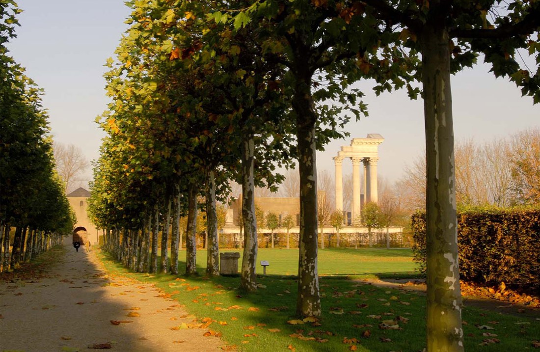 Herbstliche Bäume einer Parkallee, im Hintergrund der Hafentempel