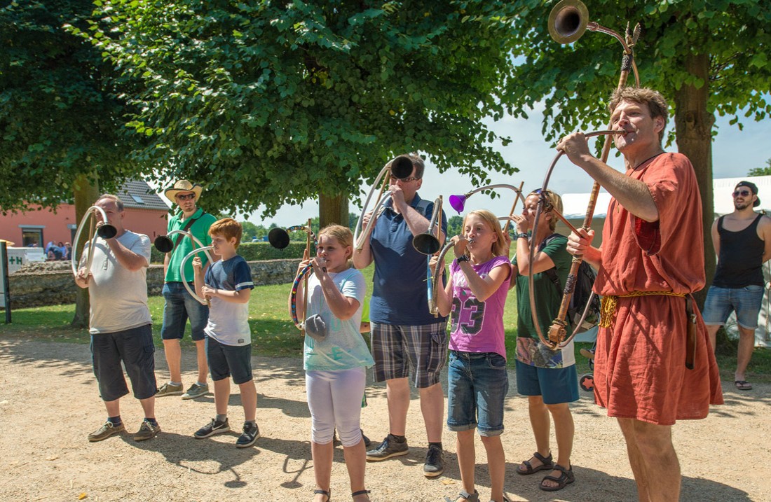 6 kinderen met zelfgemaakte muziekinstrumenten en een Romeinse Cornicen