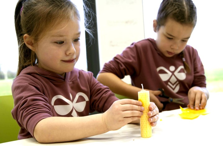 Zwei Kinder beim Zusammendrehen von Wachskerzen